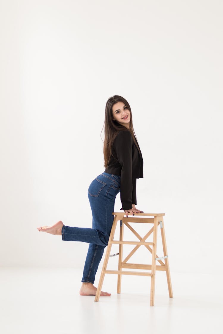 Woman In Black Sweater Posing Barefoot In Studio