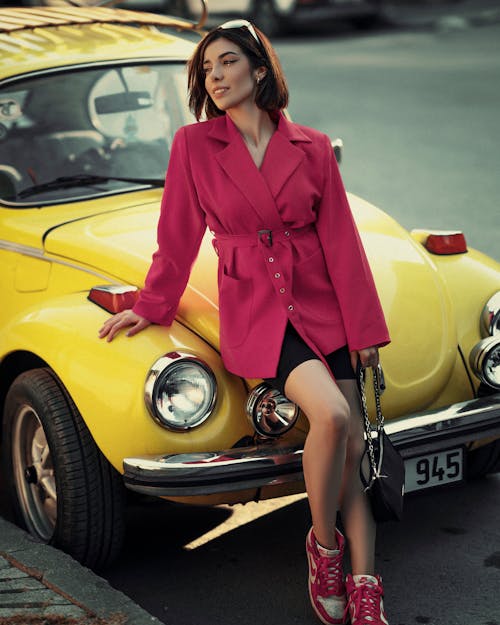 Woman in a Pink Jacket Leaning against a Vintage Car 