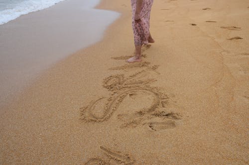 Woman Writing in the Sand with Her Foot 
