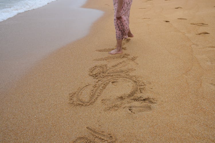 Woman Writing In The Sand With Her Foot 