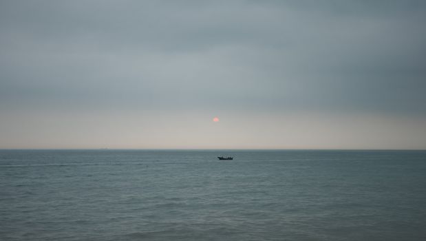 A calm ocean scene with a boat on the horizon and the sun setting. Perfect for peaceful and contemplative visuals.