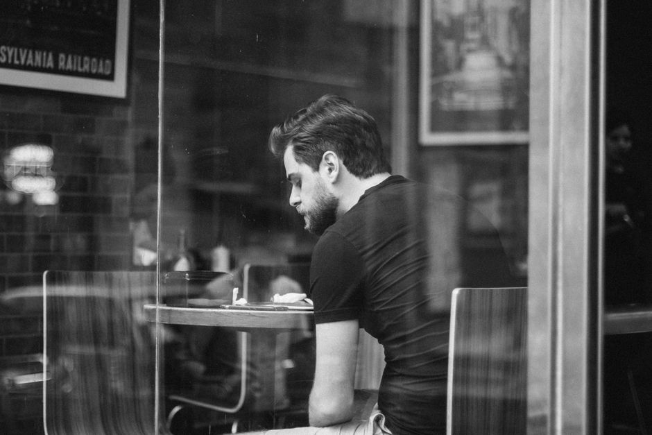 A man reflects in a café, captured in a timeless black and white photo.