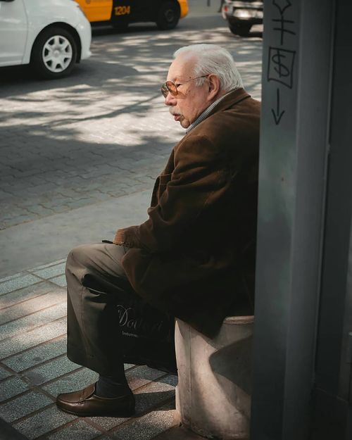 Free Senior man with sunglasses sitting on a city sidewalk in Mendoza, Argentina. Stock Photo