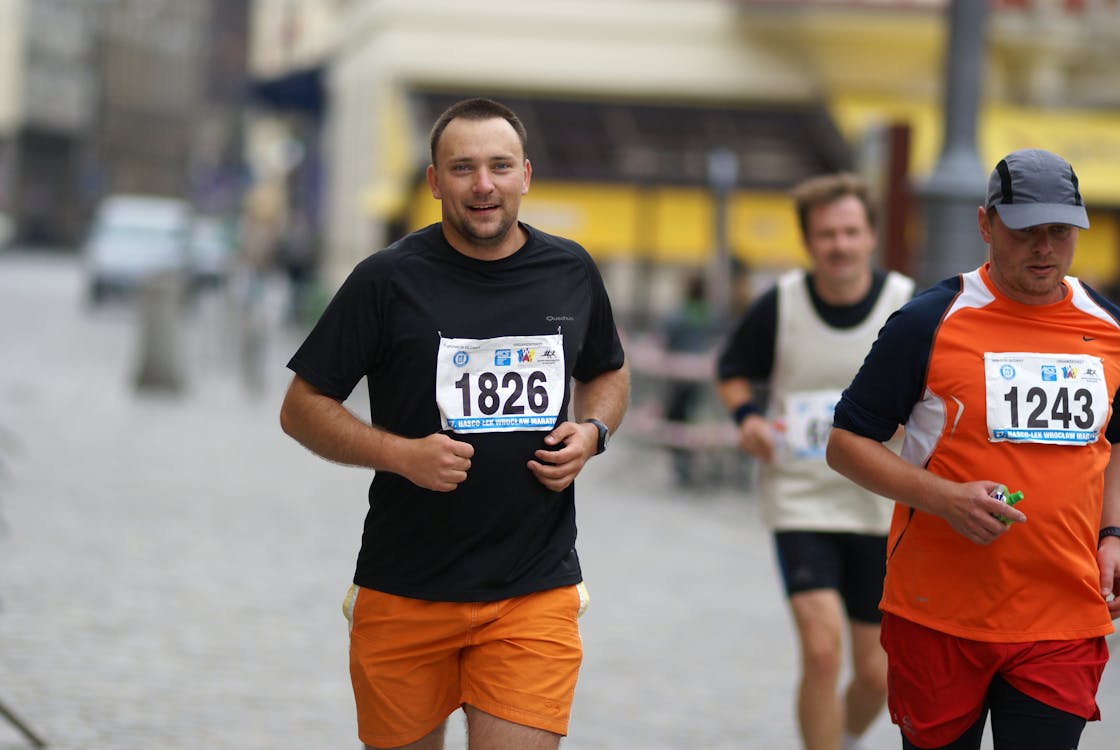 Two men running in a race on a street · Free Stock Photo