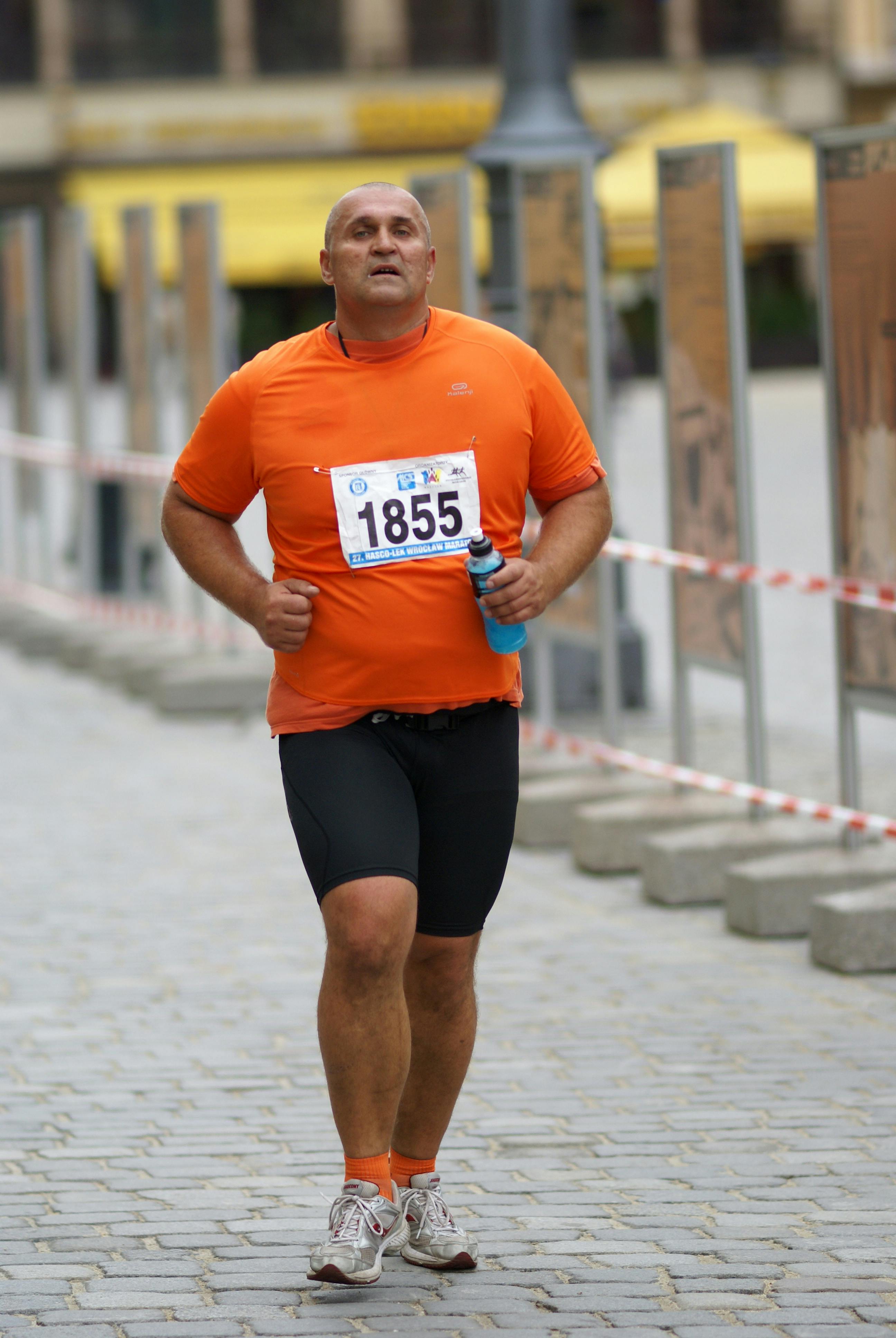 a man in an orange shirt running on a street