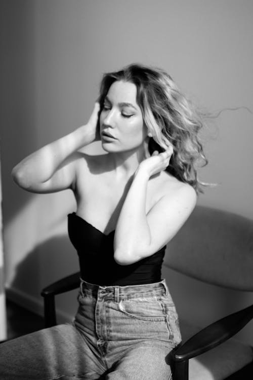 Black and White Photo of a Young Woman Fixing Her Hair