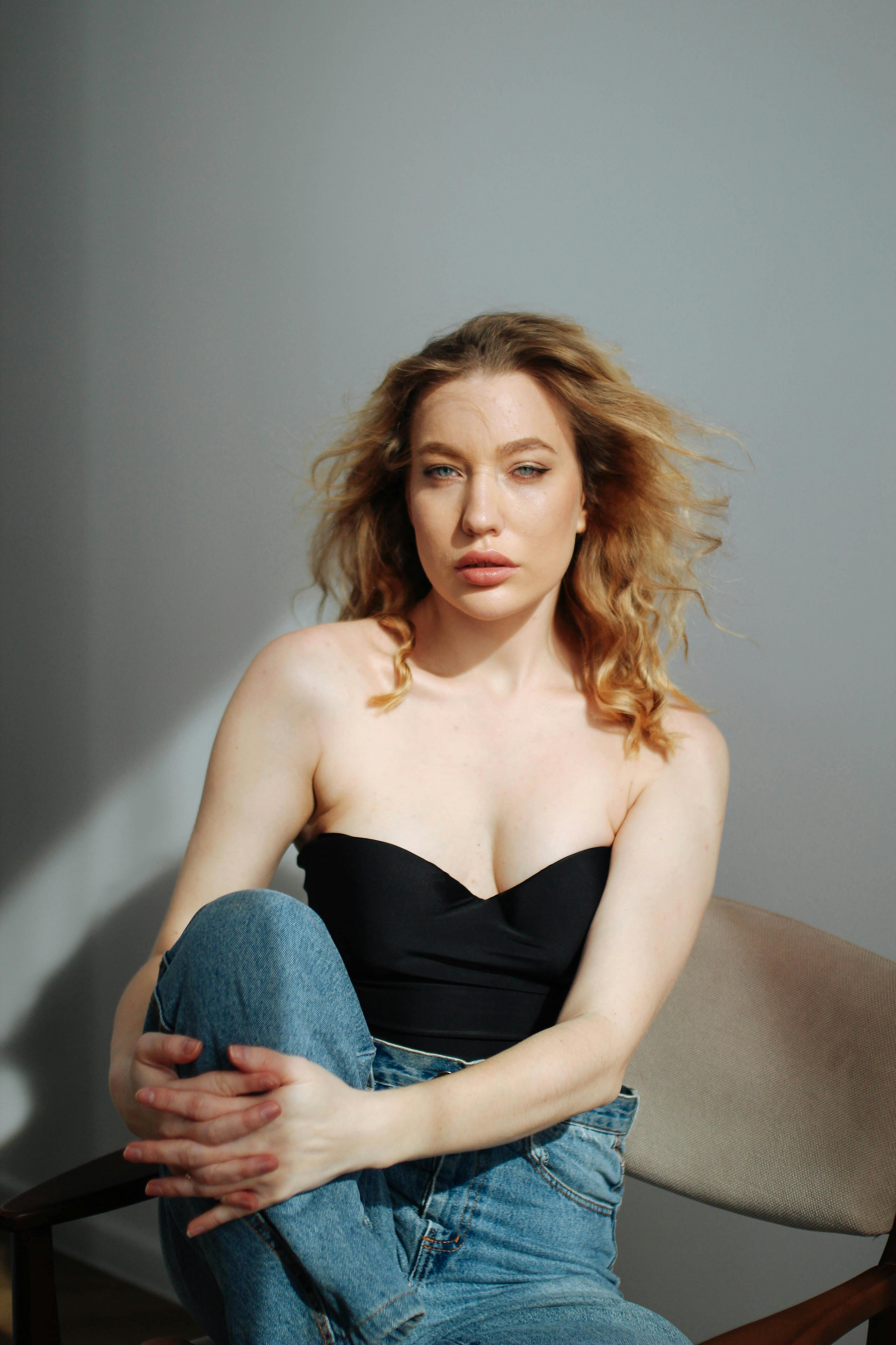 优雅的女人穿着休闲的黑色上衣和牛仔裤，在室内放松