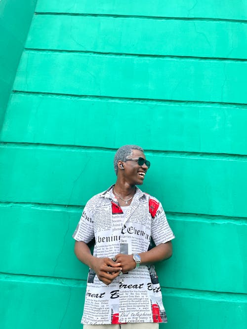 Male Model Wearing a Newspaper Themed Shirt Standing in Front of a Green Wall