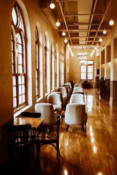 A sophisticated empty restaurant hallway with arched windows and plush seating arrangement.
