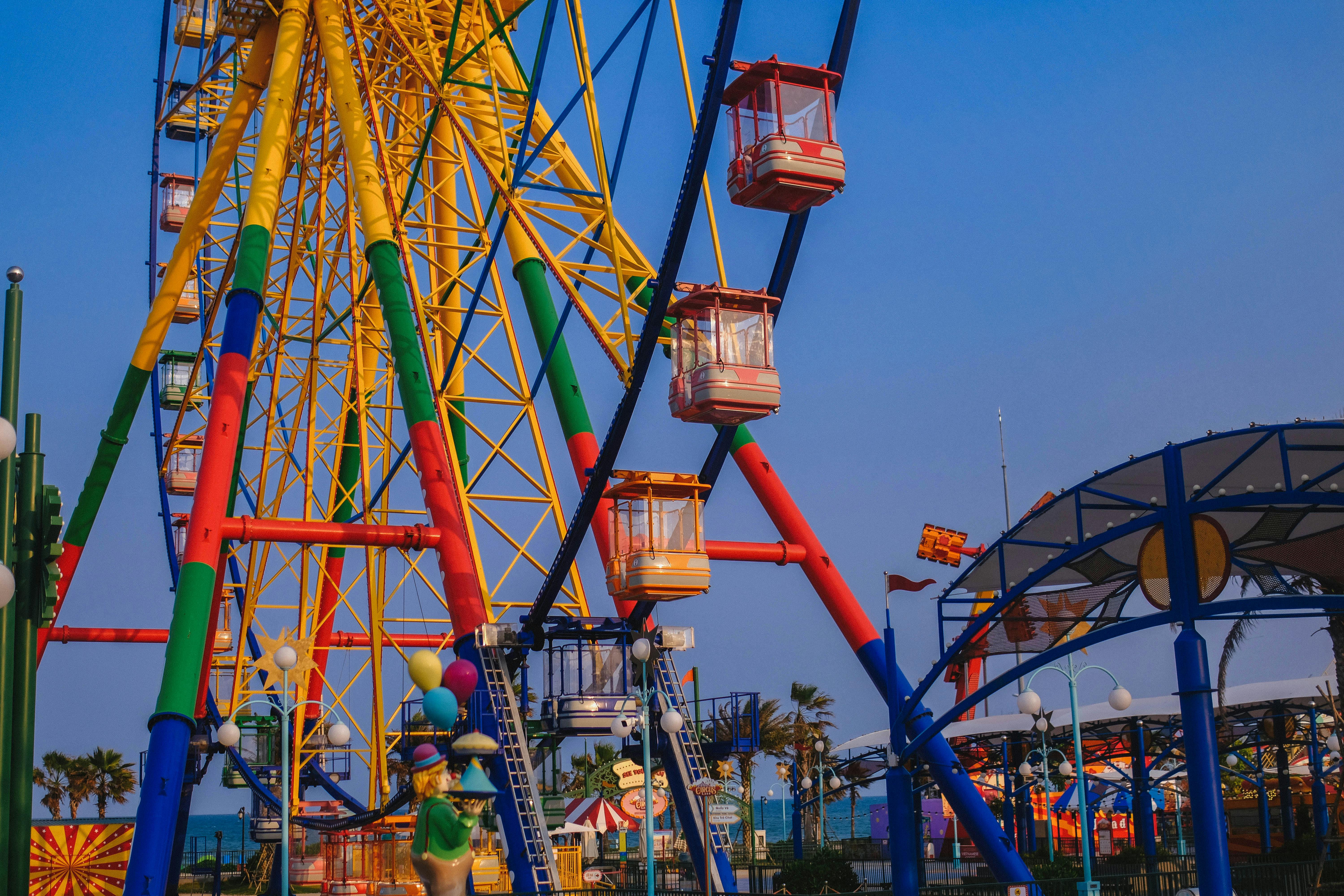 Vibrant Ferris wheel at an amusement park under a clear blue sky.