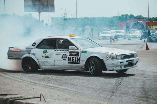 Free White sports car drifting on track with visible smoke, showcasing automotive skill and modifications. Stock Photo
