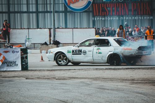 Free Action-packed drift competition featuring a Nissan Laurel with white livery at an urban track. Stock Photo