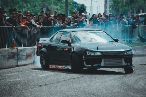 Free Black Toyota Mark II performs a drift maneuver at a crowded urban race event. Stock Photo