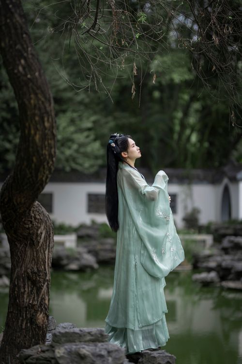 Free Woman in elegant traditional dress standing in a tranquil garden. Stock Photo