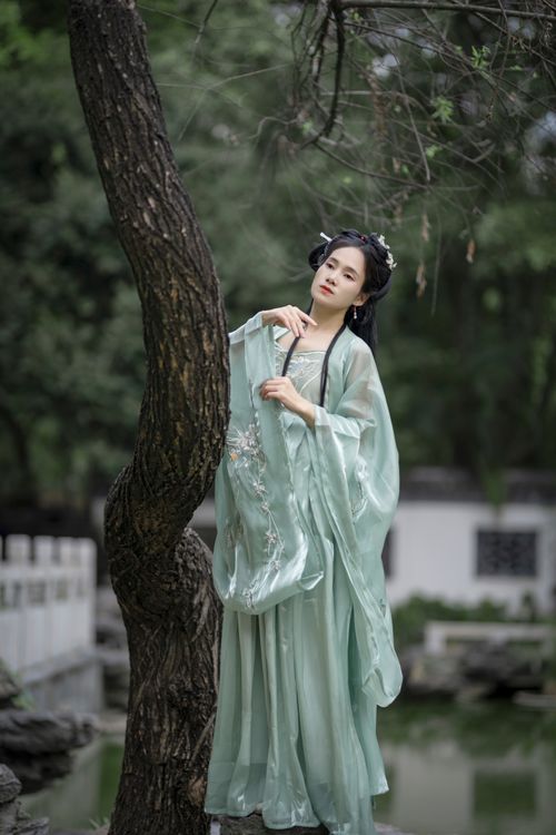 Free Elegant woman in traditional Hanfu dress, peacefully leaning on a tree in a tranquil garden. Stock Photo