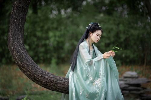 Free A woman in traditional dress seated on a tree branch in a tranquil garden setting. Stock Photo