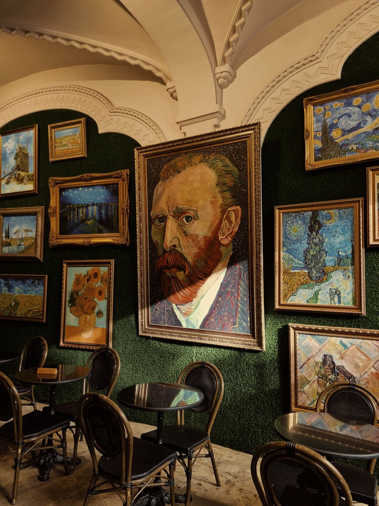 Paintings on Wall in Cafe in the style of Vincent Van Gogh. One of the paintings is of Vincent Van Gogh himself.