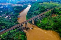 印度尼西亚辛当查亚铁路桥的鸟瞰图，展现了横跨郁郁葱葱绿色河流的风景