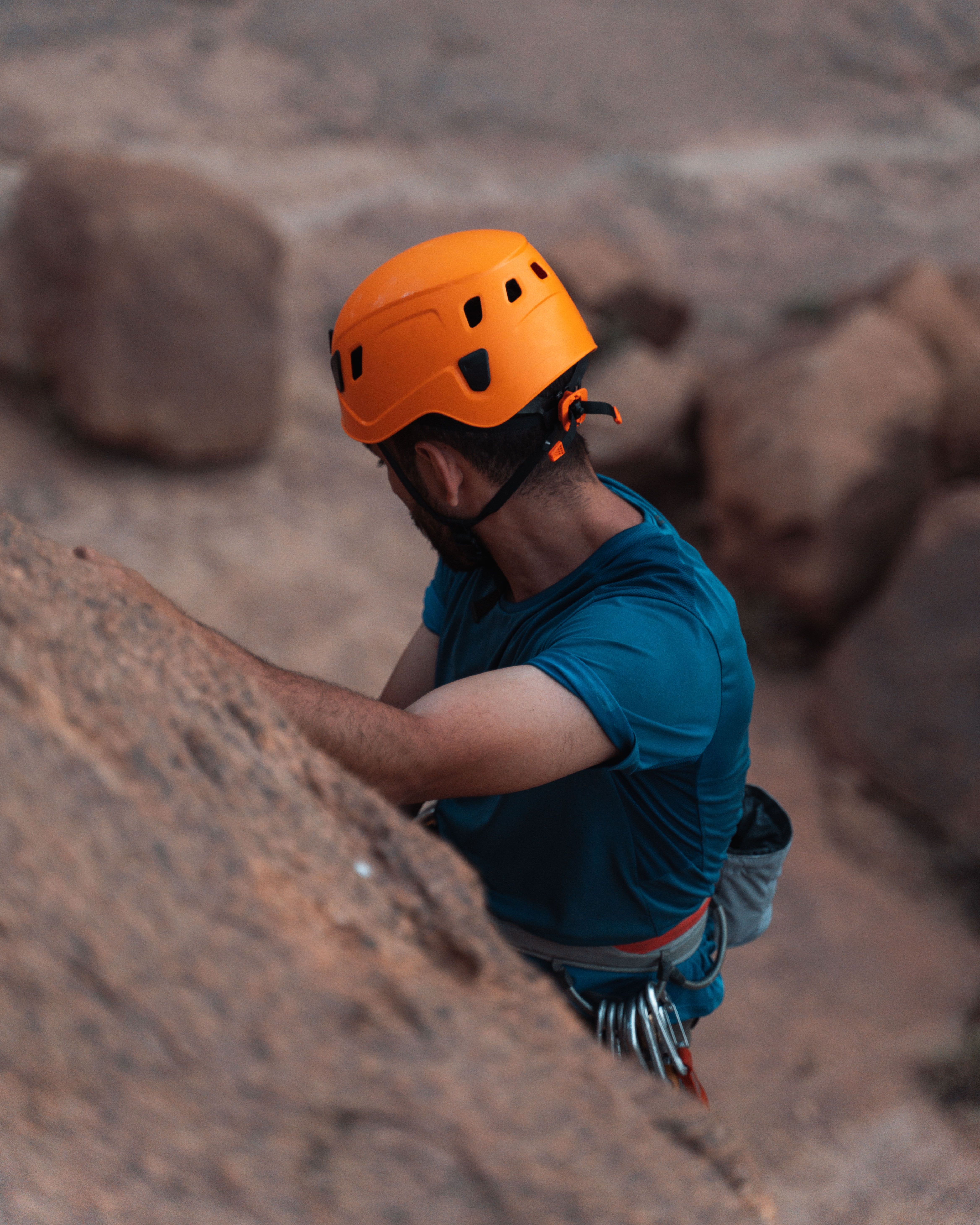 Man in helmet rock climbing with safety gear in rugged terrain