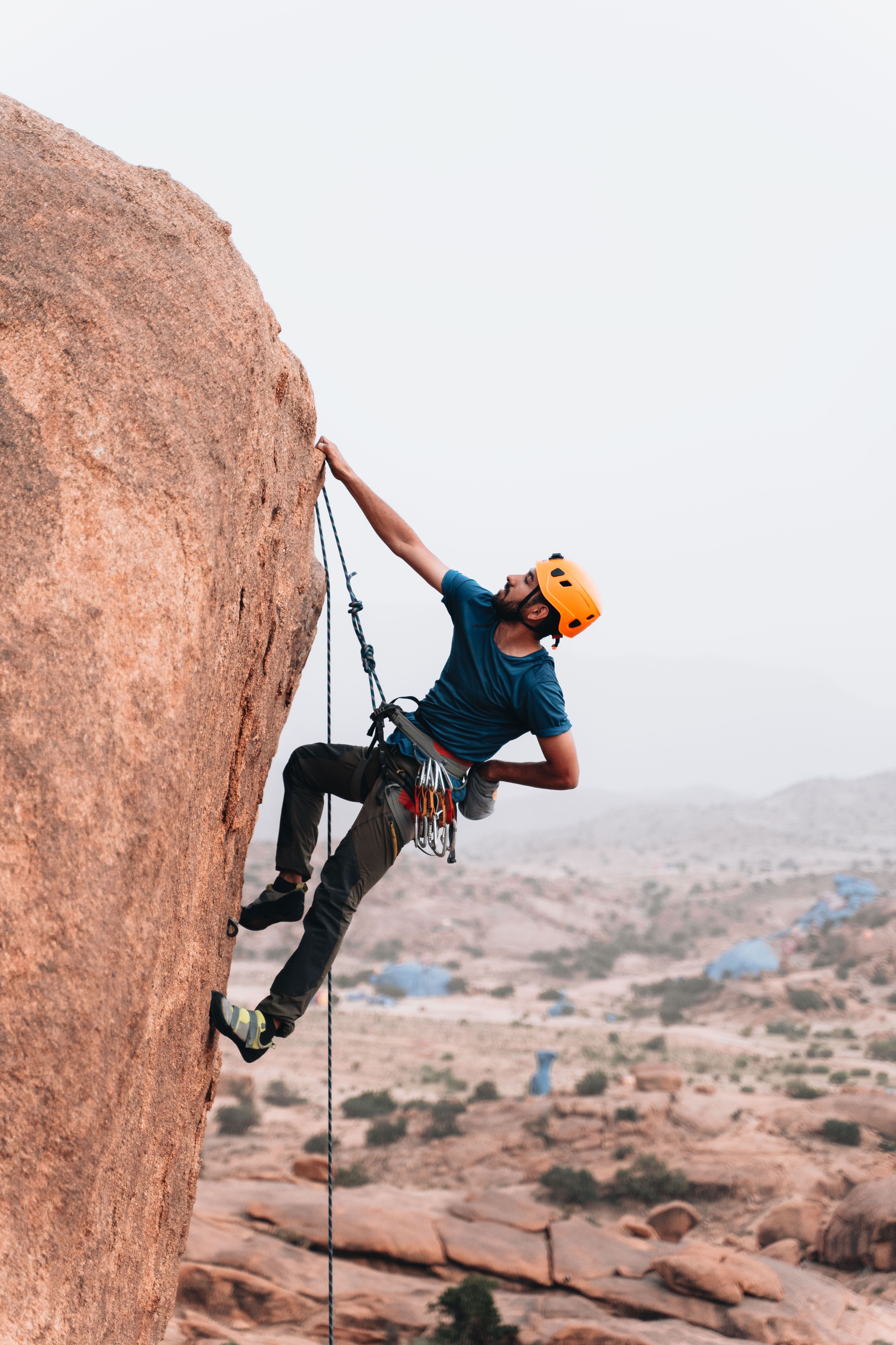 Man in climbing helmet ascending a steep rock cliff outdoors