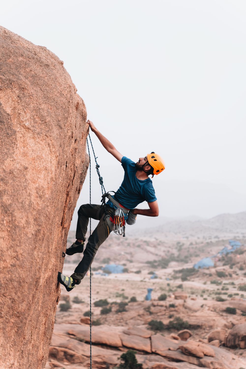 Man in climbing helmet ascending a steep rock cliff outdoors