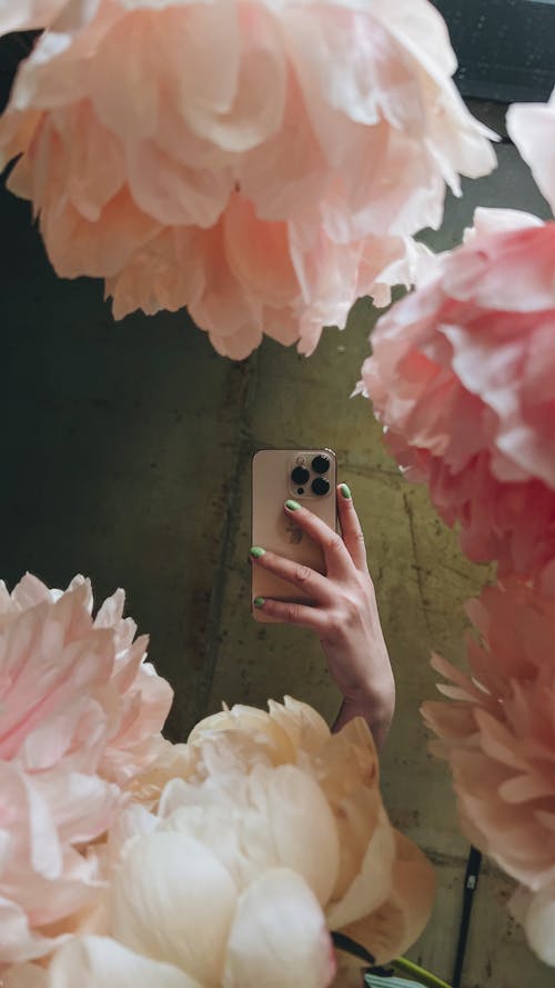 Woman Hand Holding Cellphone among Flowers