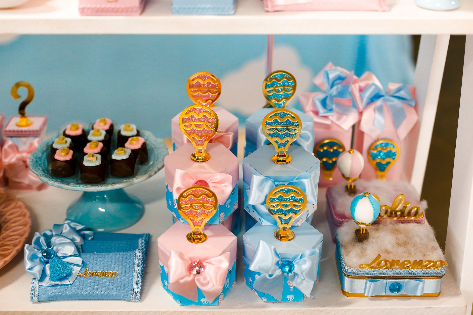 Elegant baby shower dessert table with pastel treats and hot air balloon decorations.