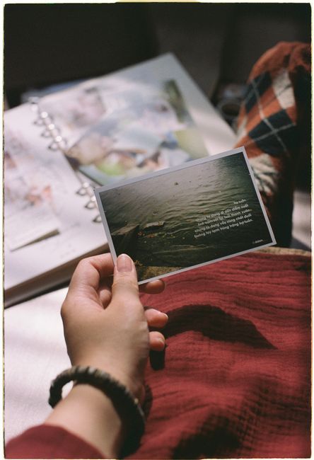 A hand holds a vintage polaroid depicting a serene water scene, creating a nostalgic vibe.
