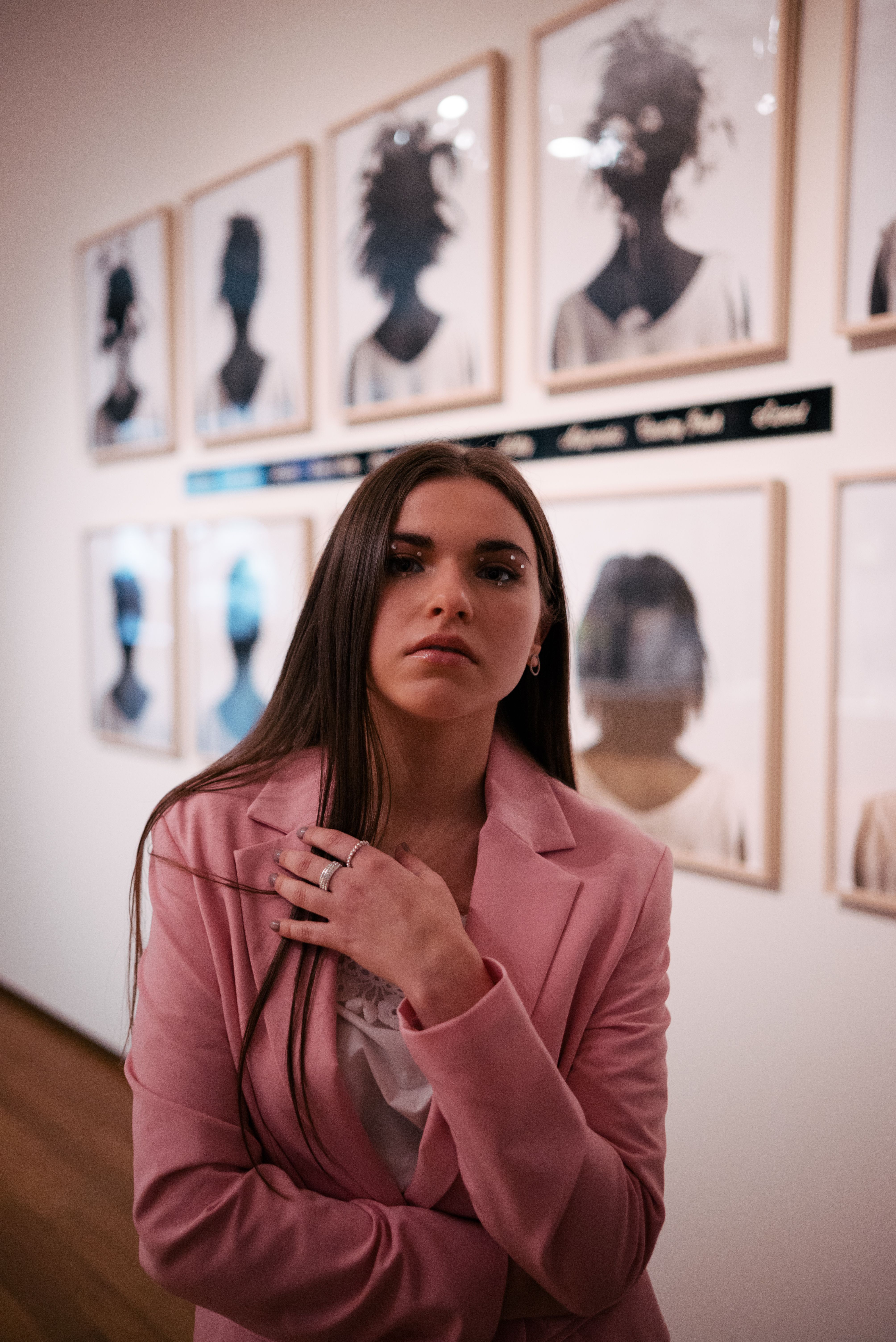 Stylish young woman in a pink suit posing confidently in an art gallery.
