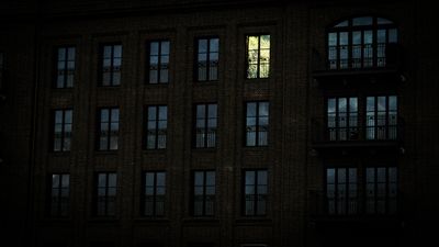 Dark building with single illuminated window — success-gallery thumbnail two