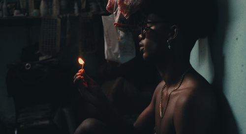 Free A person holding a lit matchstick, creating a dramatic atmosphere in a dimly lit room. Stock Photo