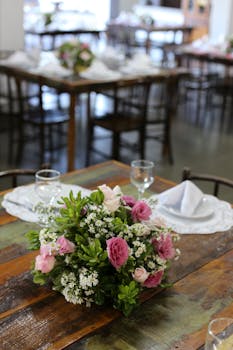质朴的木制餐桌上摆放着精美的粉色和白色花朵，很适合用餐