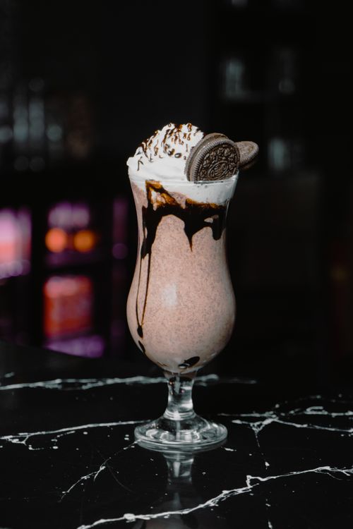 Free Indulgent chocolate milkshake topped with whipped cream and cookies, perfect for dessert lovers. Stock Photo
