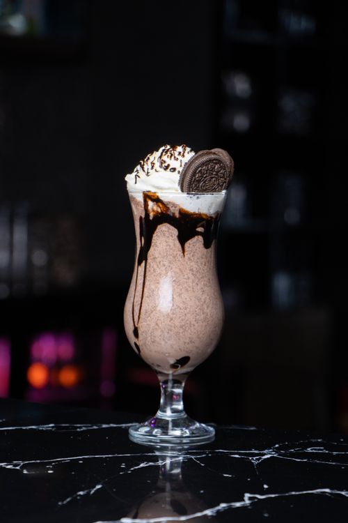 Free A mouthwatering chocolate milkshake topped with whipped cream and a cookie, drizzled with syrup. Stock Photo
