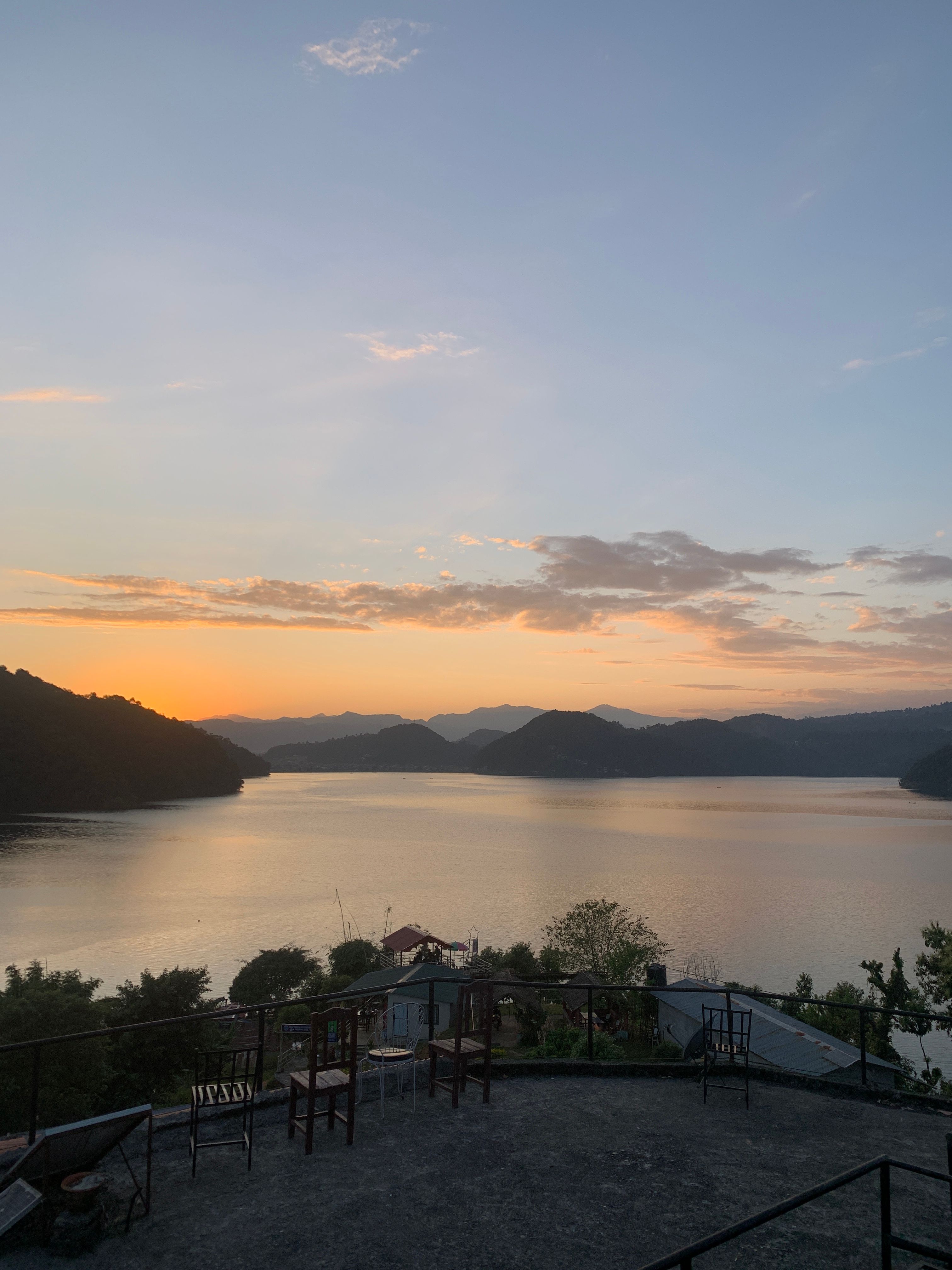 Tranquil sunset view across Phewa Lake from a cozy terrace in Nepal, ideal for relaxation.