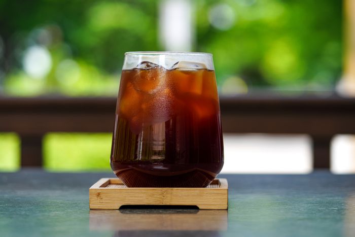 Glass of iced cola on a wooden tray outdoors