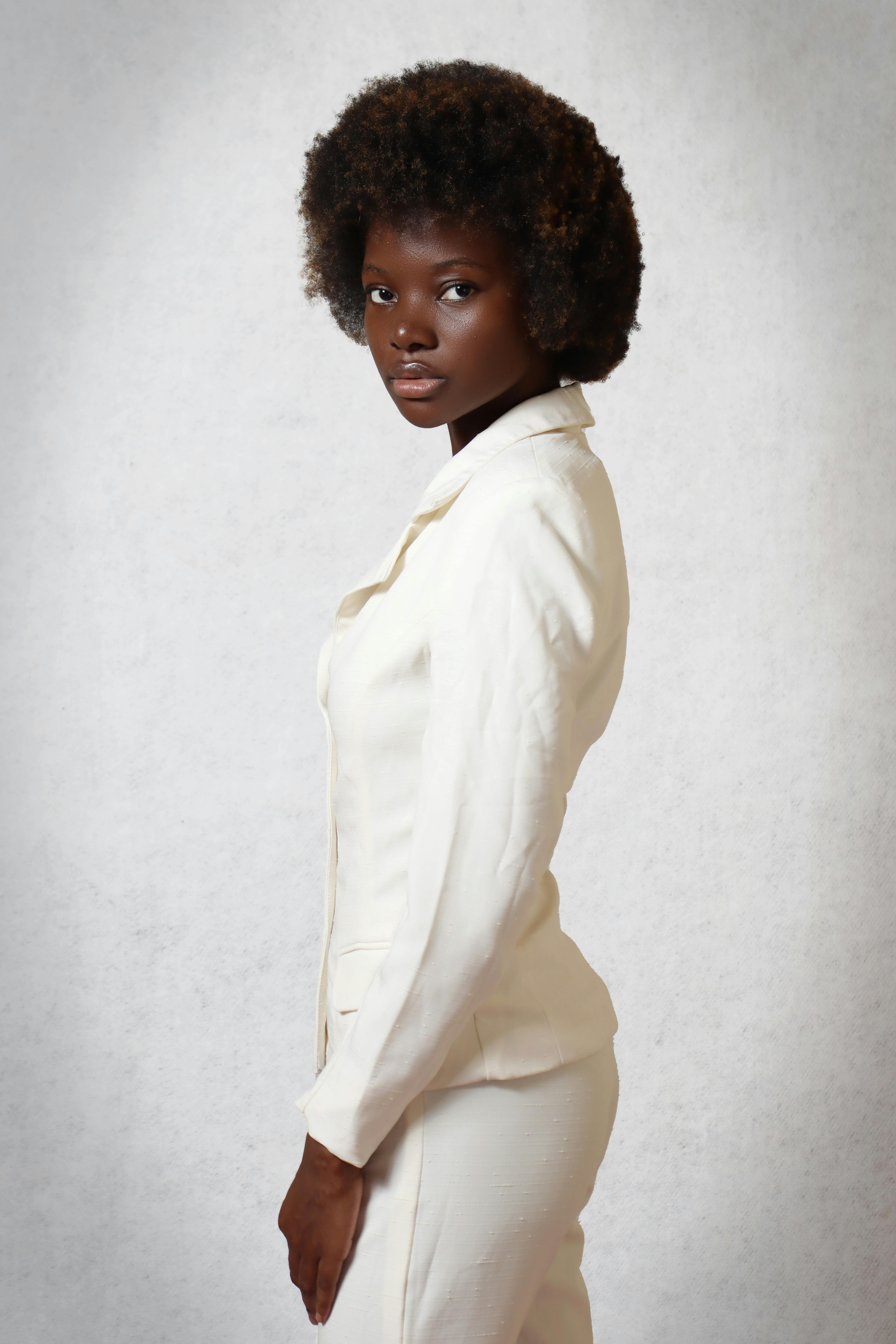 Sophisticated portrait of an African woman in a white suit with afro hair, exuding elegance.