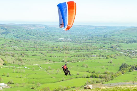 A paraglider soars over the lush green landscape of Hope Valley, England.