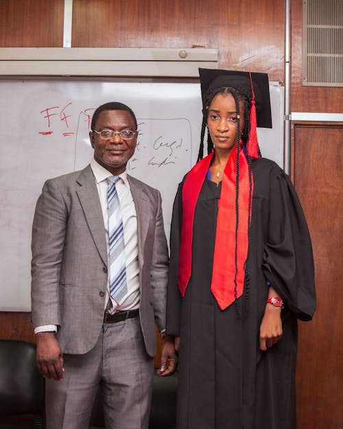 Man in Suit Posing with Graduate in Academic Hat and Gown