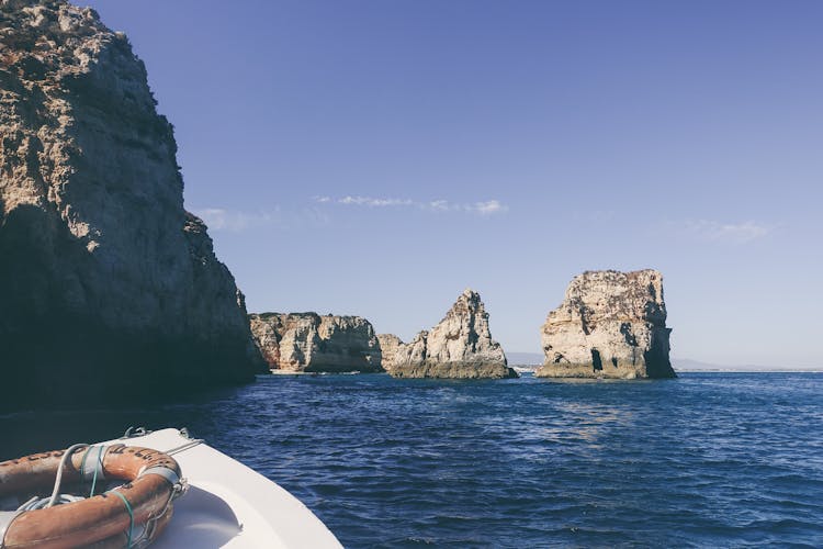 White Boat On Near Cliffs And Rock Formations