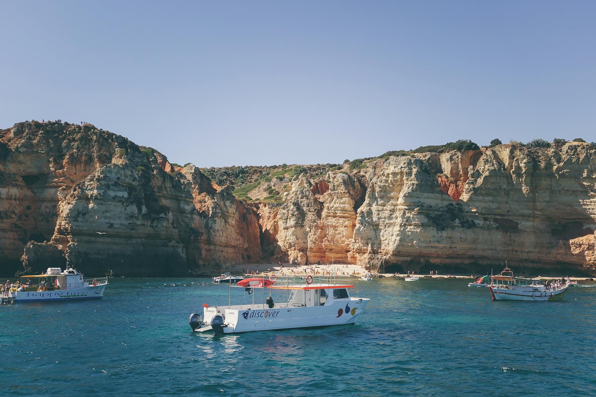 Explore the stunning rocky cliffs and clear blue waters on a boat tour under the summer sun.