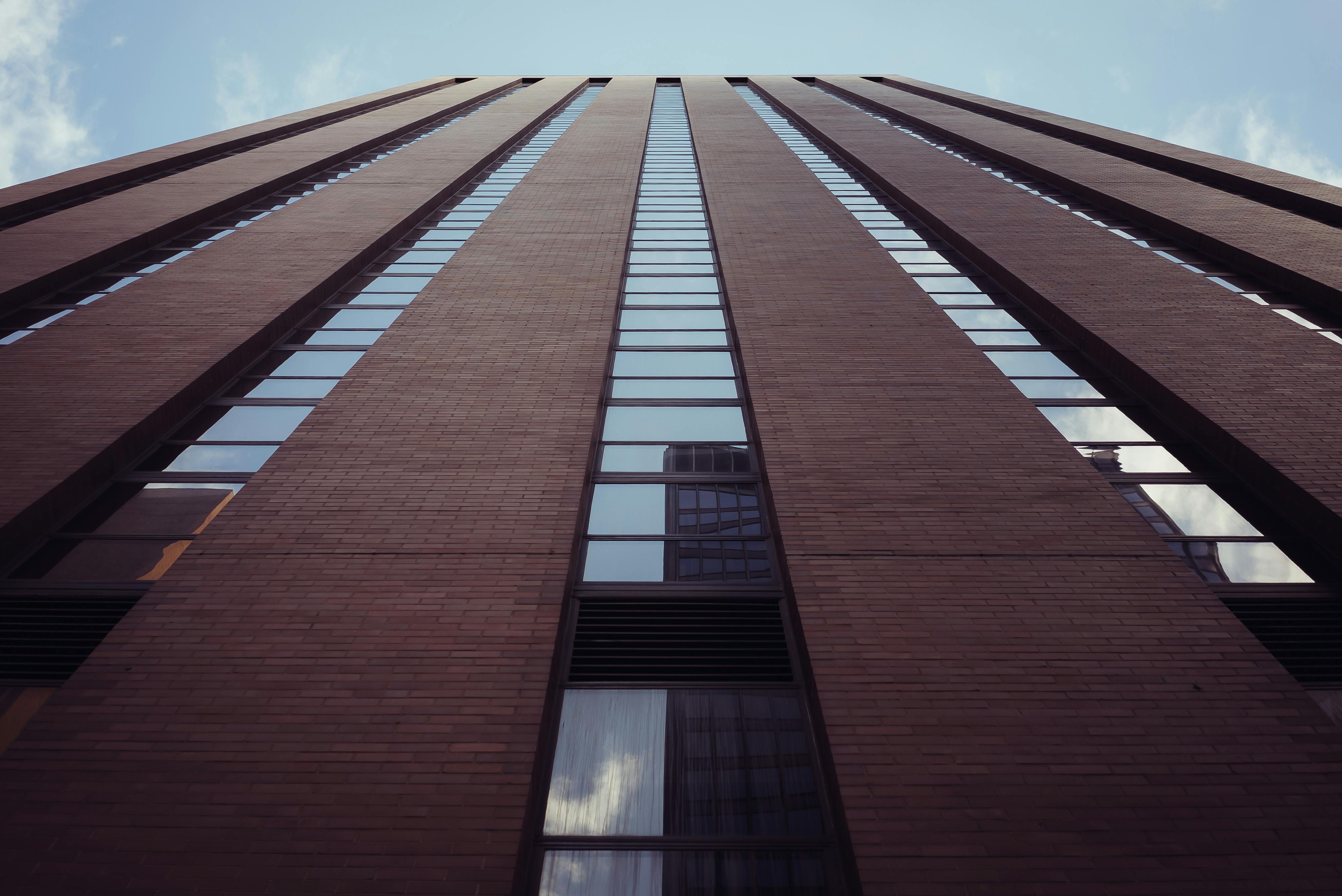 仰望一座带反光窗户的现代化摩天大楼，在晴朗的天空下