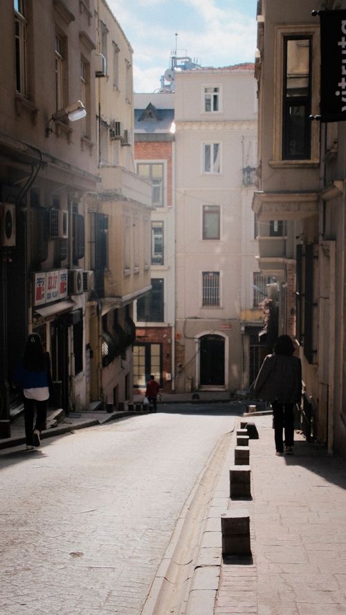 Free Charming urban street scene featuring historic buildings and pedestrians under warm sunlight. Stock Photo