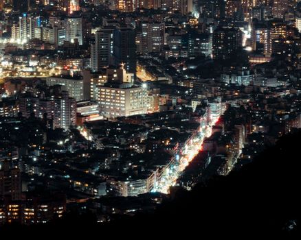 Aerial view of a vibrant city illuminated with lights at night, showcasing urban density and architecture.