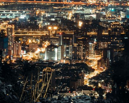 A vibrant city skyline at night with illuminated skyscrapers and bustling streets captured from above.