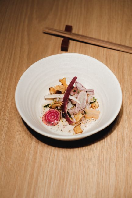 Elegant Japanese dish with sliced vegetables in a bowl, accompanied by chopsticks.