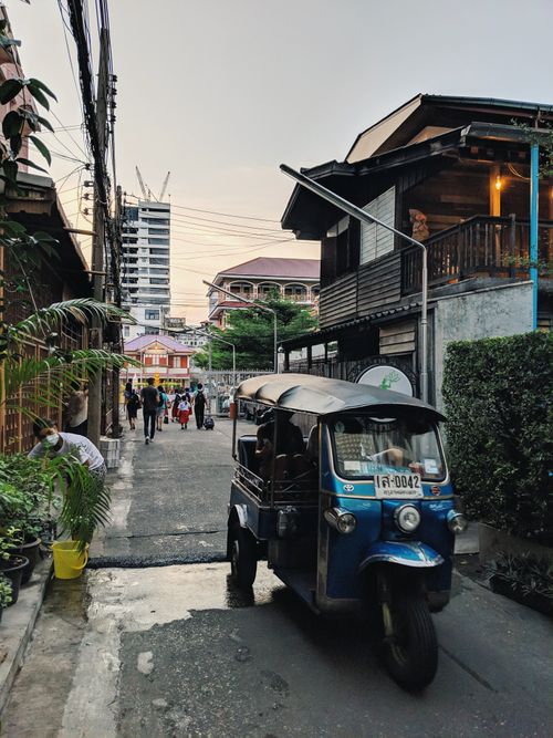 Free Bangkok street scene featuring a tuk-tuk amidst traditional and modern architecture. Stock Photo