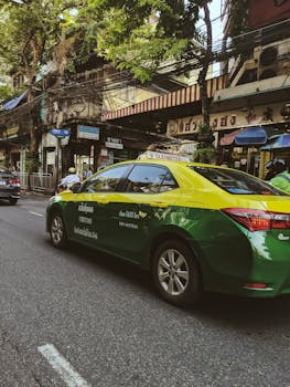 在曼谷三潘塔旺的彩色街景中，一辆绿色和黄色的泰国出租车驶过