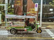 一辆色彩缤纷的嘟嘟车行驶在泰国曼谷阴雨绵绵的街道上，展现了当地的交通风貌