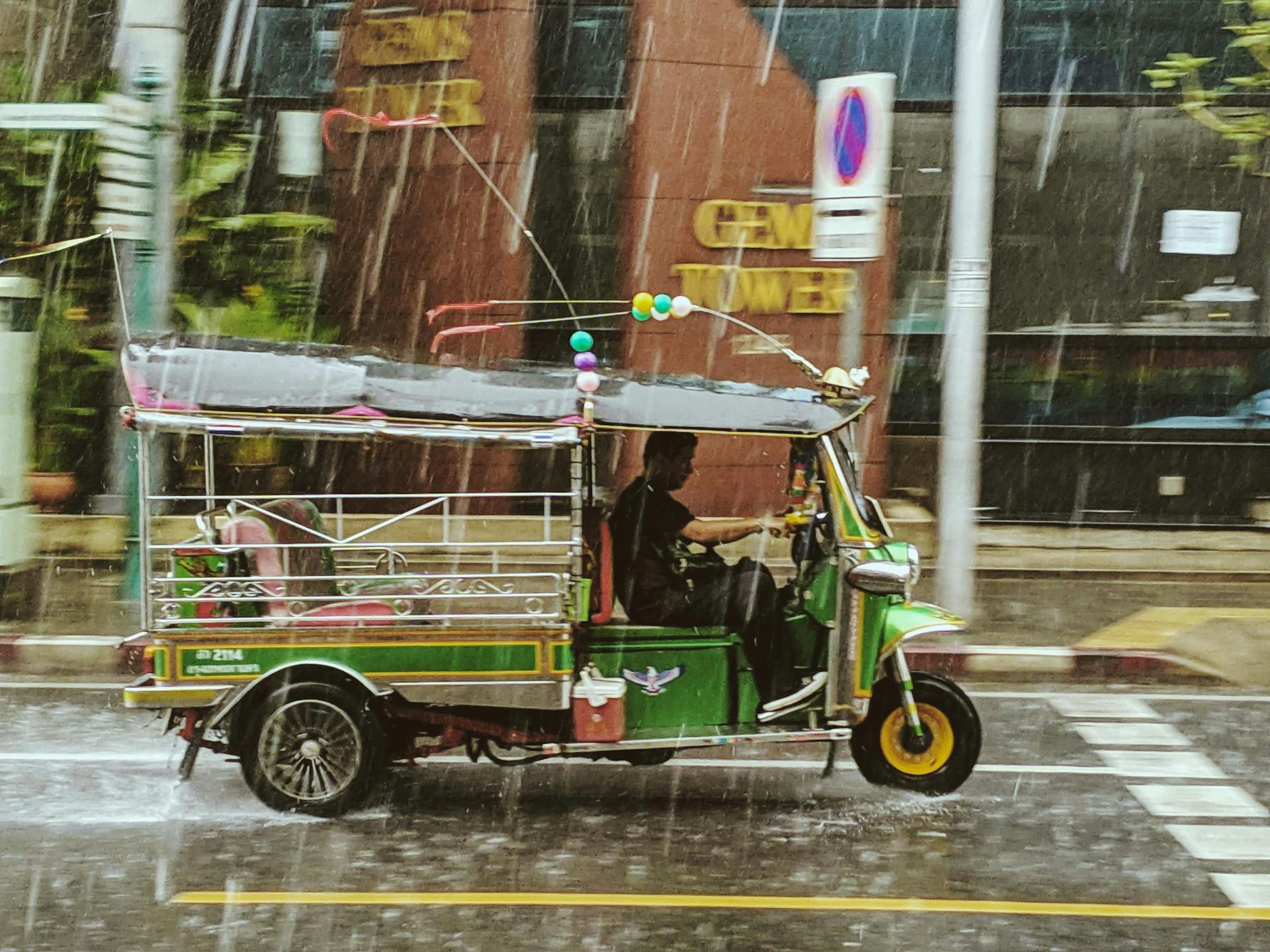 A colorful tuk tuk navigating the rainy streets of Bangkok, Thailand, showcasing local transportation.